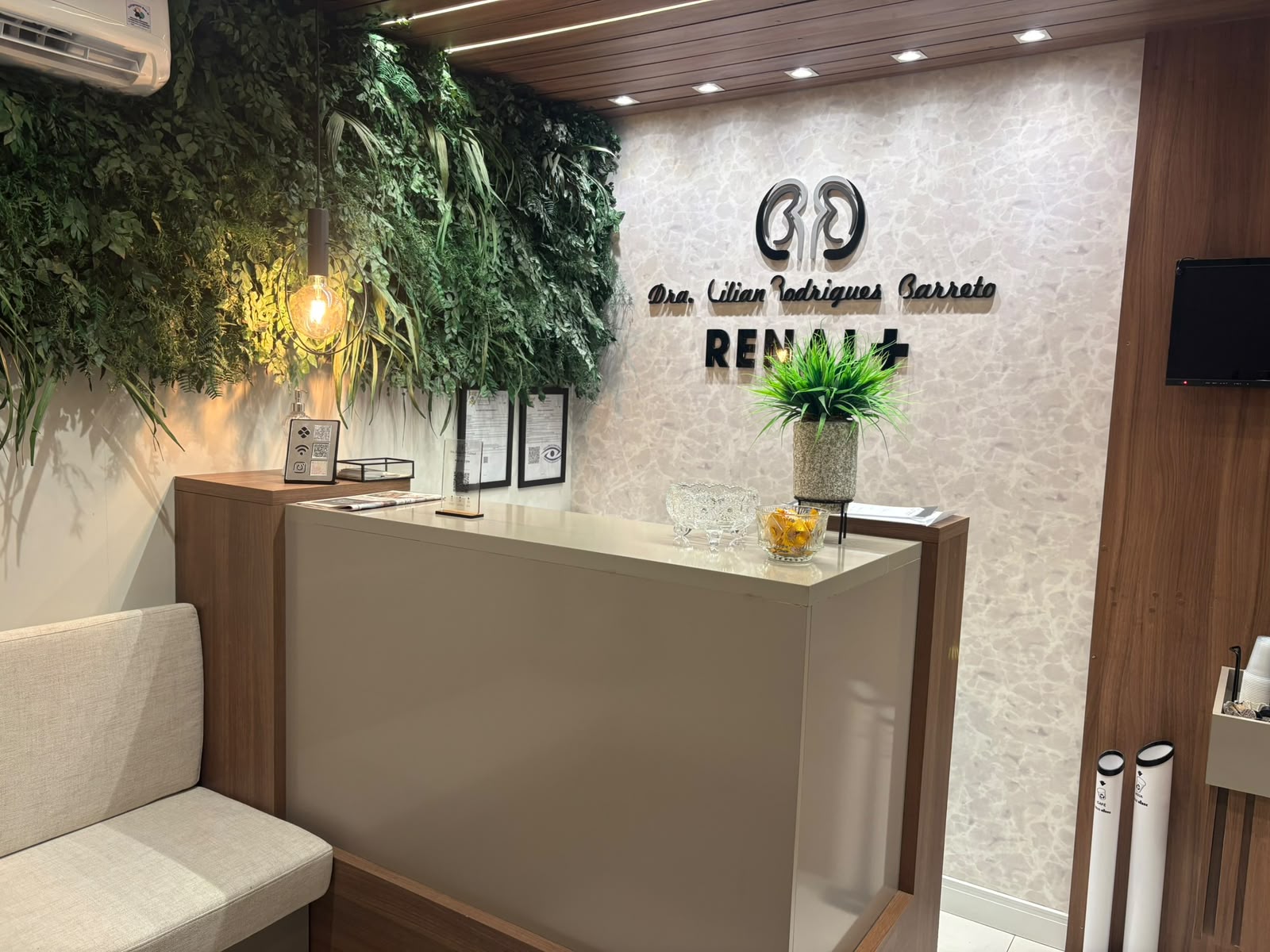 Recepção da clínica RENAL+, com jardim vertical e balcão de atendimento